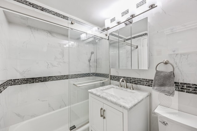 bathroom with toilet, vanity, tile walls, bath / shower combo with glass door, and decorative backsplash