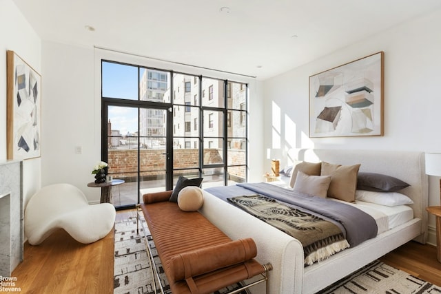 bedroom featuring hardwood / wood-style floors, a premium fireplace, and floor to ceiling windows