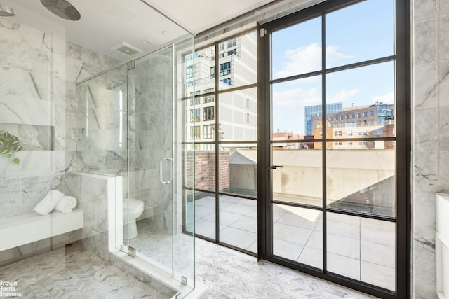 bathroom with a shower with door and toilet