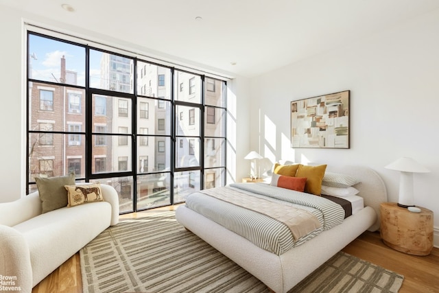 bedroom featuring multiple windows, hardwood / wood-style flooring, and a wall of windows