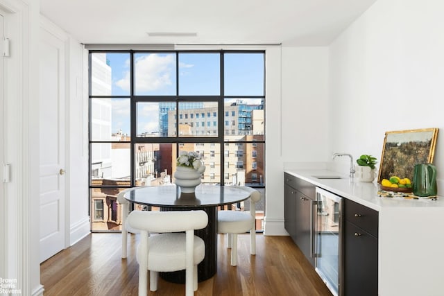 dining space with dark wood-type flooring, floor to ceiling windows, sink, and wine cooler