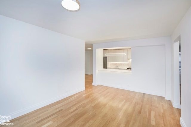 spare room featuring baseboards and light wood-type flooring