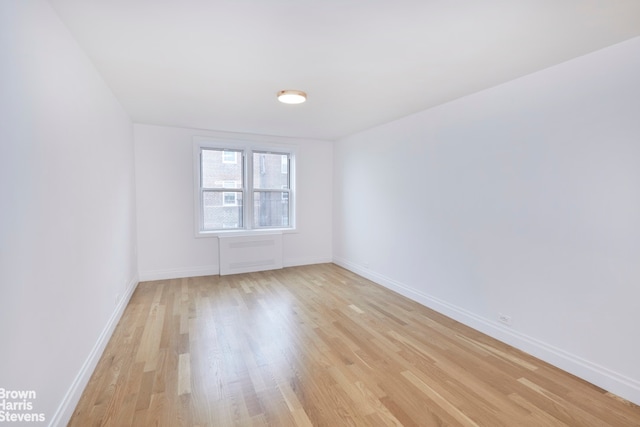 spare room with baseboards and light wood-style flooring