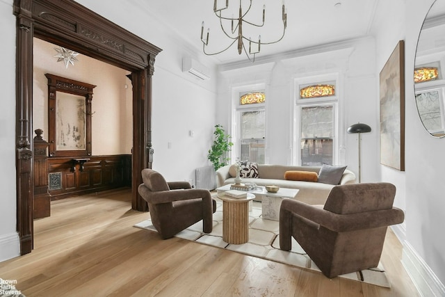 living area featuring crown molding, a chandelier, a wall mounted AC, and light hardwood / wood-style floors