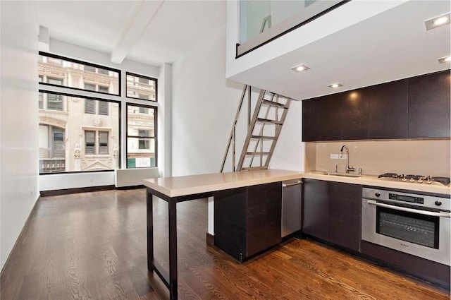 kitchen with dark wood finished floors, appliances with stainless steel finishes, light countertops, and a sink