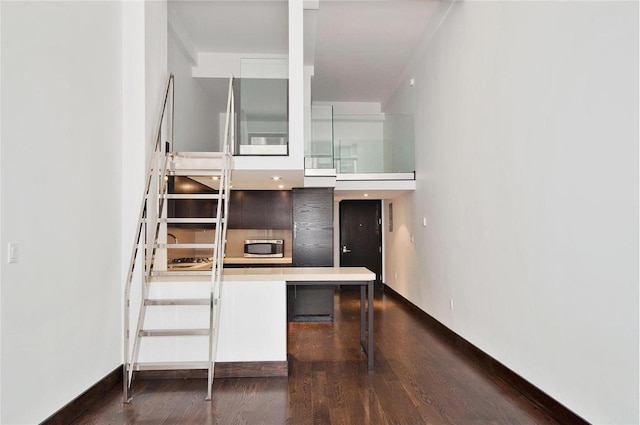 kitchen featuring modern cabinets, stainless steel microwave, a breakfast bar, dark wood-style flooring, and light countertops