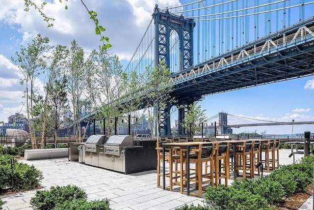 view of community with a patio, exterior bar, fence, a city view, and exterior kitchen