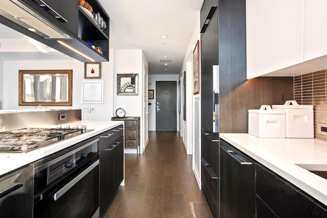 kitchen featuring dark wood-style floors, stainless steel gas cooktop, dark cabinetry, light countertops, and oven