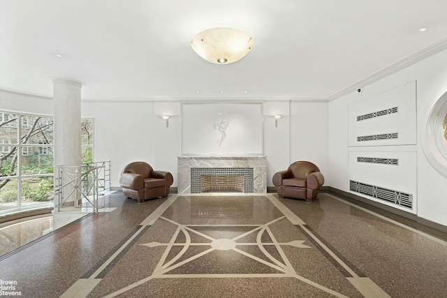 living area with crown molding, baseboards, ornate columns, and a fireplace