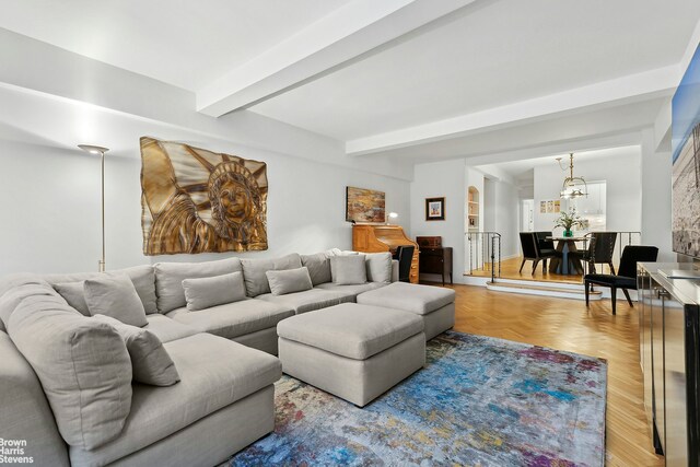 living area with beamed ceiling and an inviting chandelier