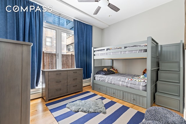 bedroom featuring ceiling fan, a baseboard heating unit, and wood finished floors