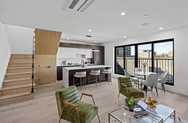 living room featuring light wood-type flooring, stairs, visible vents, and recessed lighting