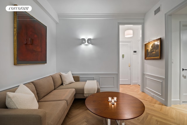 living area with visible vents, ornamental molding, a decorative wall, and a wainscoted wall