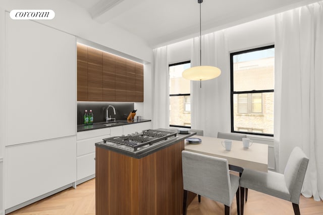 kitchen with a sink, dark countertops, visible vents, modern cabinets, and pendant lighting