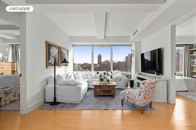 living area featuring beam ceiling, wood finished floors, and visible vents