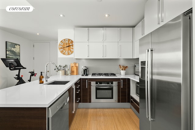 kitchen with light wood finished floors, visible vents, appliances with stainless steel finishes, a sink, and a peninsula