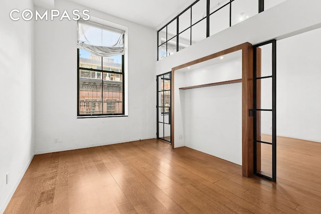 unfurnished bedroom featuring hardwood / wood-style flooring and a high ceiling