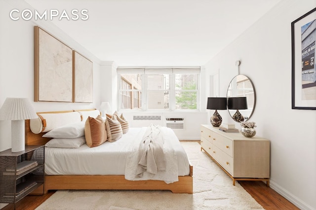 bedroom featuring hardwood / wood-style flooring and a wall unit AC