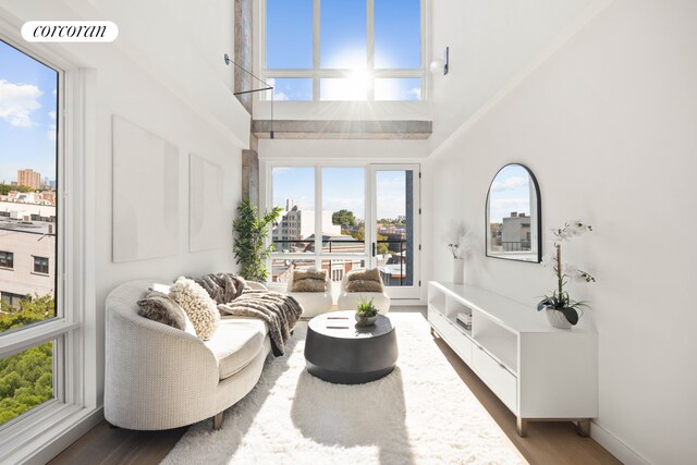 living area featuring baseboards, visible vents, a high ceiling, and wood finished floors