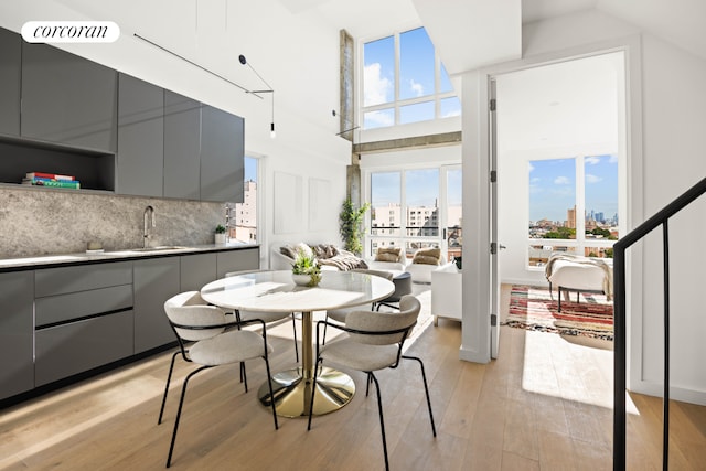 dining room with a city view, a towering ceiling, visible vents, and light wood finished floors