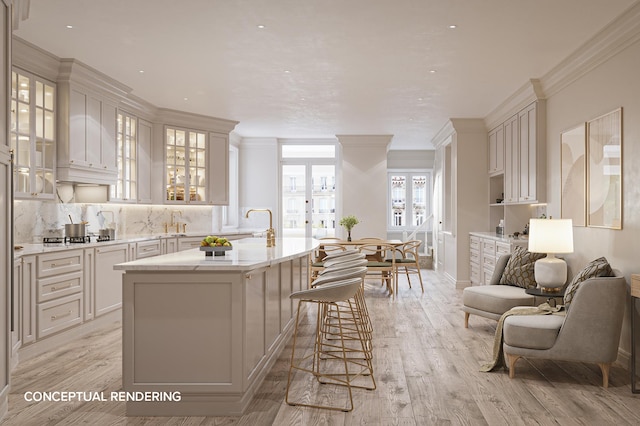 kitchen with light wood-style flooring, a breakfast bar, a kitchen island with sink, crown molding, and backsplash