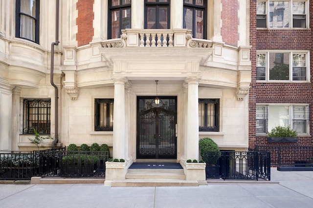 property entrance featuring french doors, a balcony, and stone siding