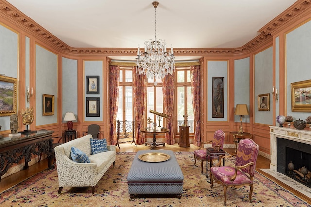 living area with a wainscoted wall, a decorative wall, an inviting chandelier, a fireplace with flush hearth, and wallpapered walls