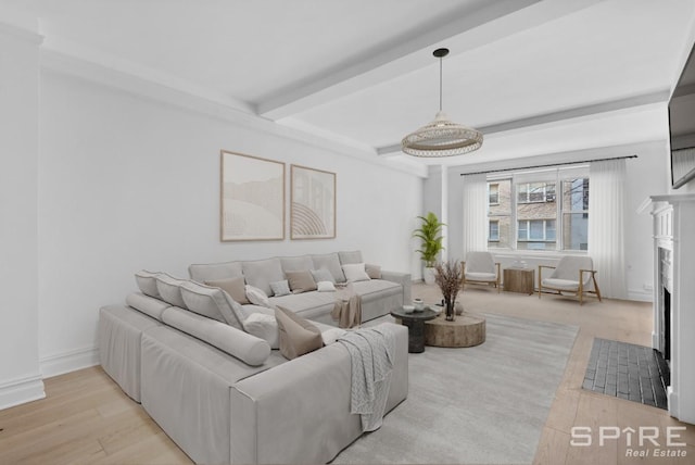 living area with light wood-type flooring, a premium fireplace, baseboards, and beamed ceiling