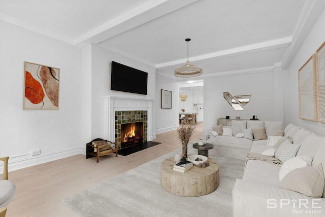 living area featuring a fireplace, baseboards, beamed ceiling, and wood finished floors