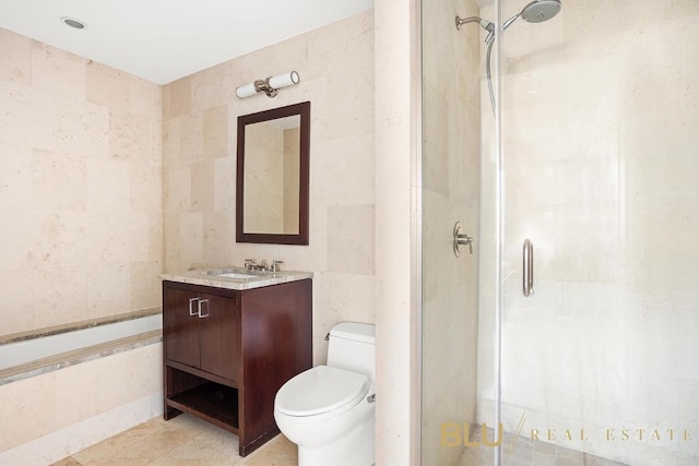 bathroom with toilet, vanity, a shower stall, and tile walls