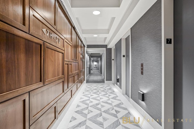 hall with recessed lighting and a tray ceiling