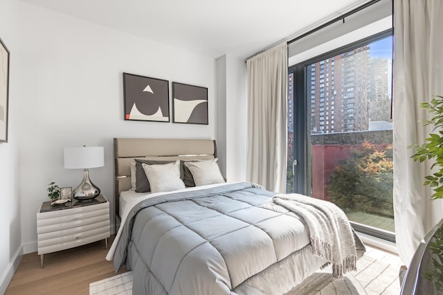 500 W 45th St Unit 207, New York City, NY 10036 - bedroom featuring wood finished floors, baseboards, and a view of city