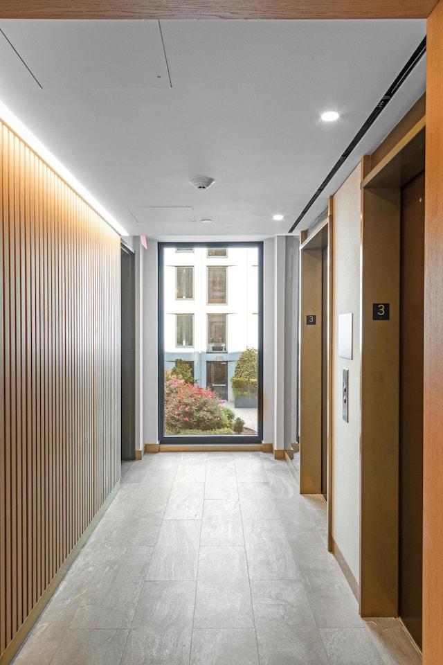 corridor featuring elevator and baseboards