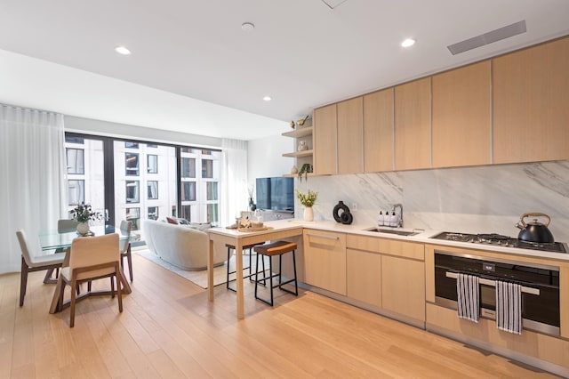 kitchen with light brown cabinets, appliances with stainless steel finishes, open shelves, decorative backsplash, and light wood finished floors