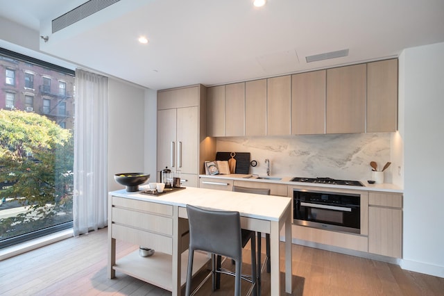 kitchen with a sink, black oven, modern cabinets, and light countertops