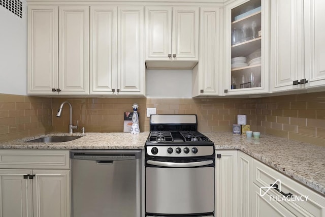 kitchen with glass insert cabinets, appliances with stainless steel finishes, white cabinets, and a sink