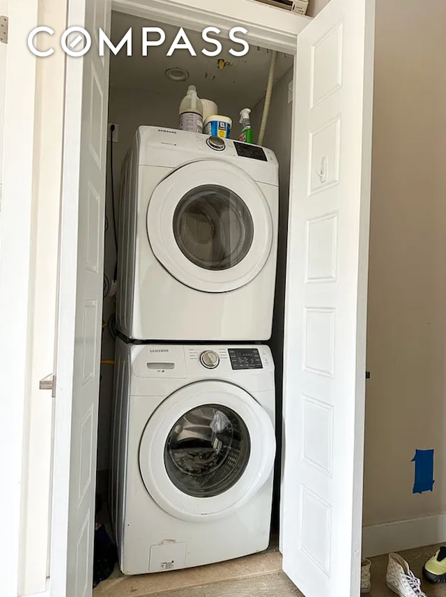 washroom with baseboards, stacked washer and clothes dryer, and laundry area