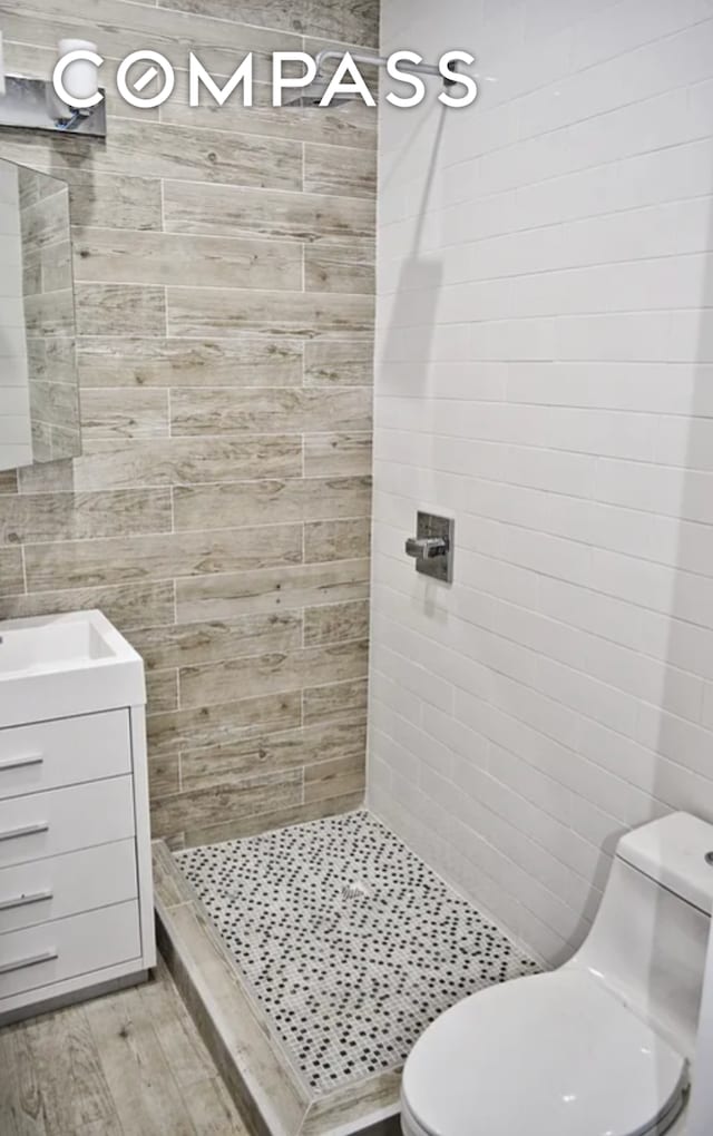 bathroom featuring a stall shower, toilet, vanity, and wood finished floors