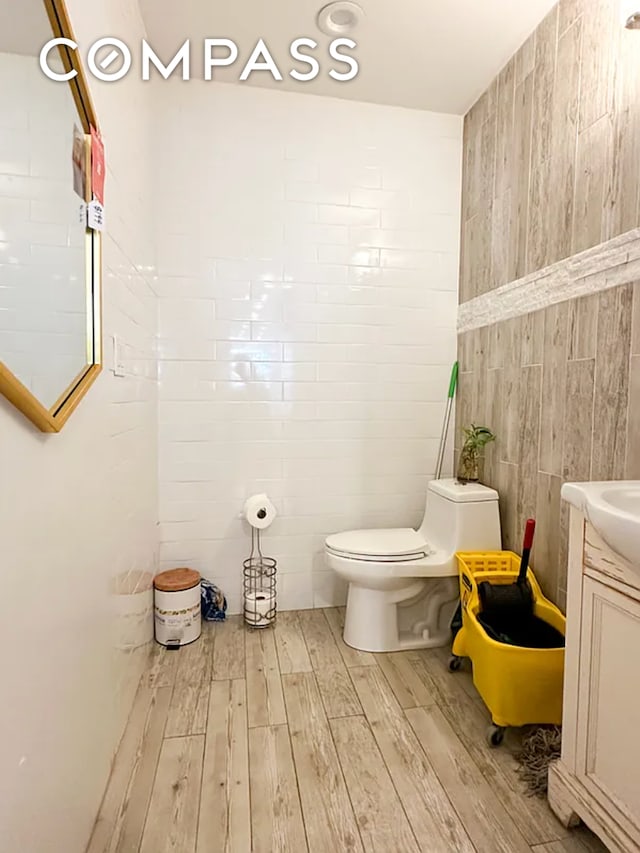 bathroom with vanity, tile walls, toilet, and wood finished floors