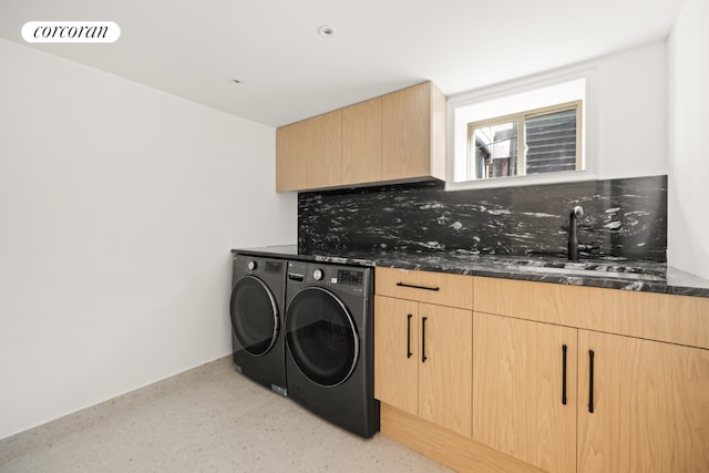 clothes washing area featuring washing machine and clothes dryer, sink, and cabinets