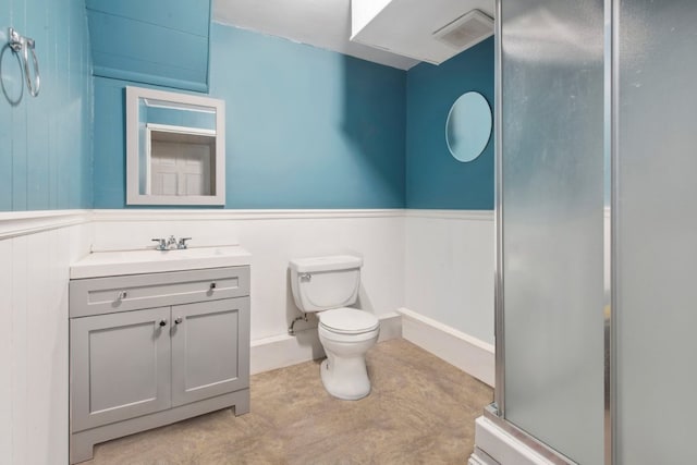 bathroom featuring visible vents, toilet, wainscoting, vanity, and a shower stall