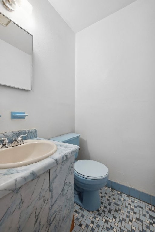 bathroom featuring baseboards, vanity, and toilet