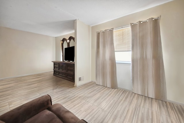 living area with baseboards and visible vents