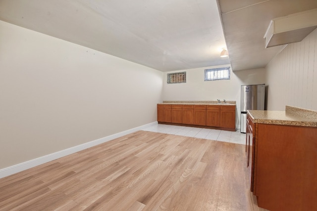 additional living space with light wood-type flooring, a sink, and baseboards