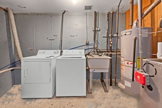 clothes washing area with water heater, laundry area, a sink, and washing machine and dryer