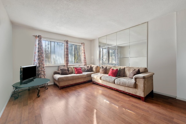 living room featuring a textured ceiling, baseboards, and wood finished floors