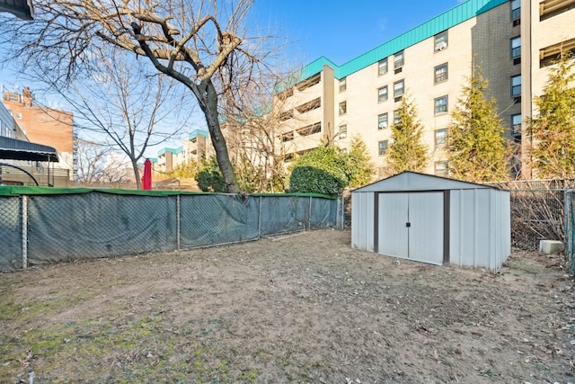 view of yard featuring fence, a storage unit, and an outbuilding