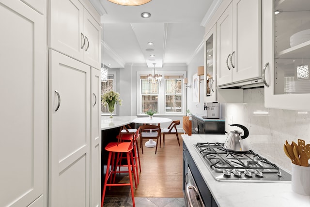 66 Madison Ave Unit 1A, New York City, NY 10016 - kitchen featuring stainless steel gas stovetop, white cabinetry, ornamental molding, tasteful backsplash, and glass insert cabinets