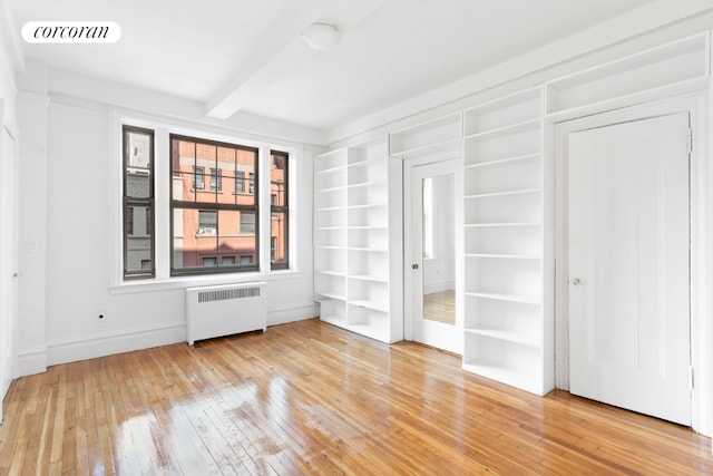 unfurnished room with beamed ceiling, radiator, and hardwood / wood-style flooring