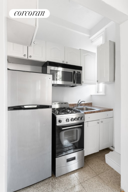 kitchen featuring stainless steel appliances, white cabinetry, and sink